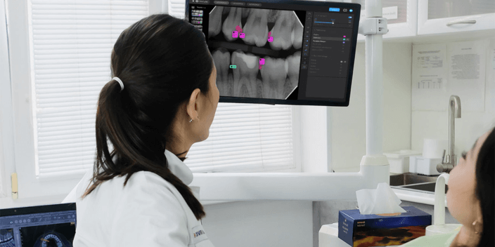 A dentist and patient look at a scan of teeth