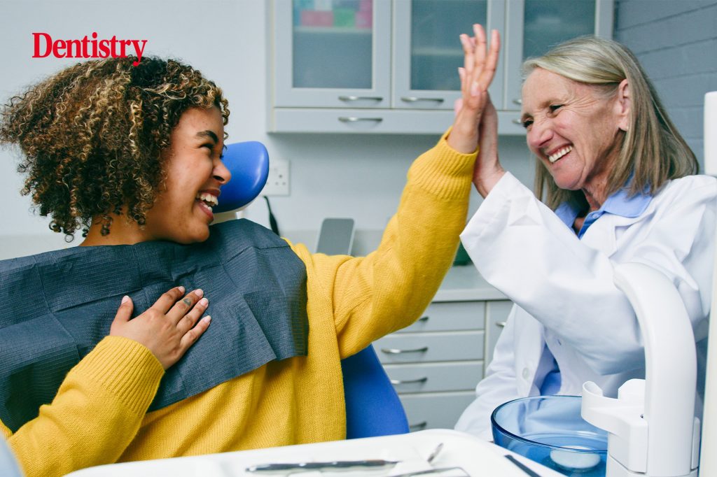 Dentist and patient high fiving at dental practice following successful treatment