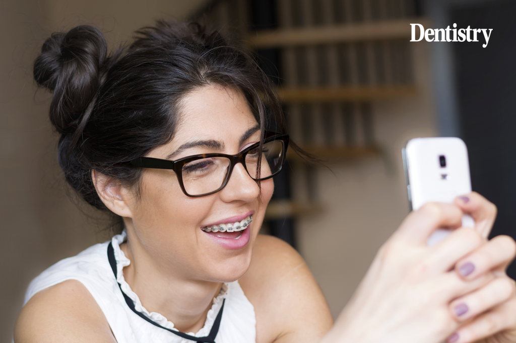 Current image: Young woman with braces using a mobile phone to research orthodontic treatment