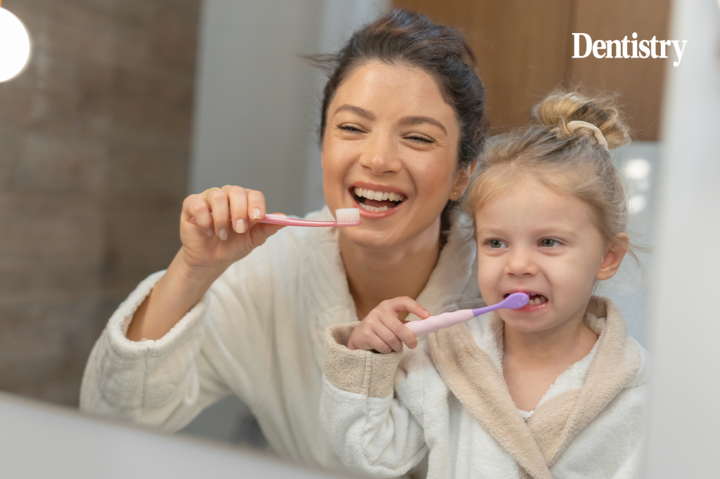 Current image: Mother and child practice good oral health by brushing teeth. 'Lack of political will' blamed as child tooth decay admissions rise